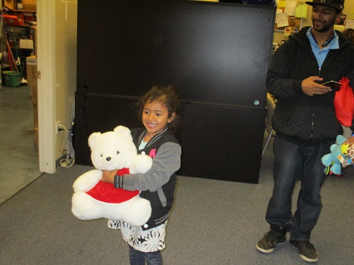 A little girl is smiling holding a Teddy Bear